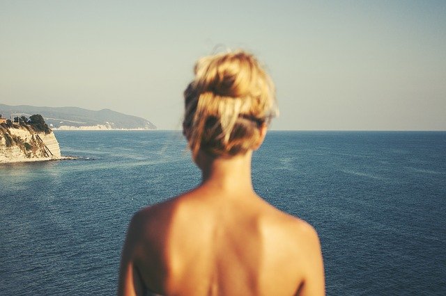 Detail na šiju ženy, ktorá stojí a pozerá na more.jpg