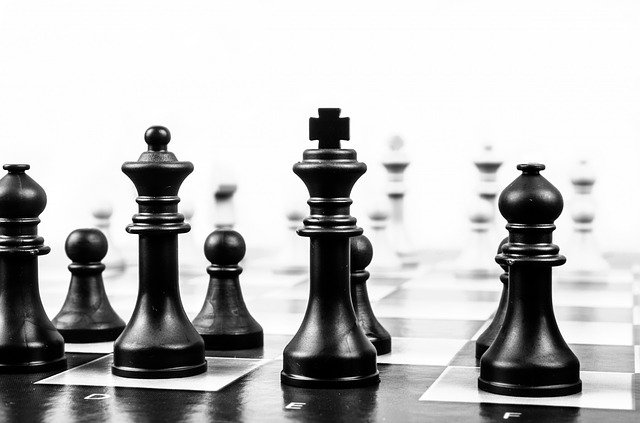 Čierne figúrky rozostavené na čierno-bielej šachovnici.jpg